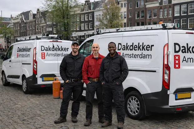 Het team van Dakdekker Amsterdam bij hun bedrijfsbussen