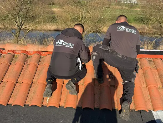 Twee dakdekkers van Top Roof aan het werk op een pannendak